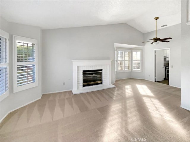 unfurnished living room featuring a fireplace, light colored carpet, a wealth of natural light, and vaulted ceiling