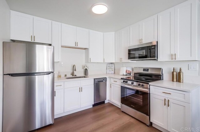 kitchen featuring appliances with stainless steel finishes, dark hardwood / wood-style flooring, white cabinetry, and sink