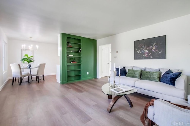 living room featuring built in features, a notable chandelier, and hardwood / wood-style floors