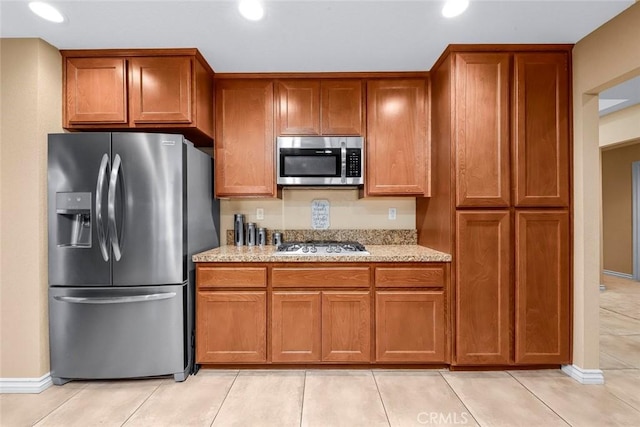 kitchen featuring light tile patterned floors, light stone countertops, and appliances with stainless steel finishes