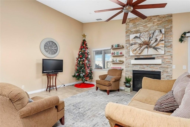 tiled living room with ceiling fan, vaulted ceiling, and a stone fireplace