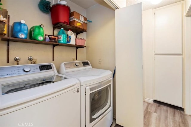 clothes washing area with light hardwood / wood-style flooring and washing machine and dryer