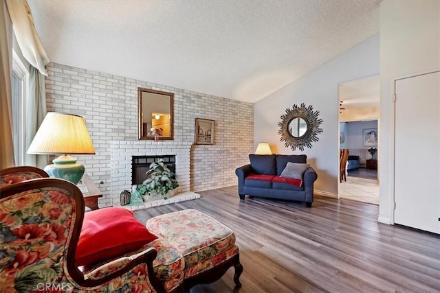 living room with a fireplace, hardwood / wood-style floors, a textured ceiling, brick wall, and lofted ceiling