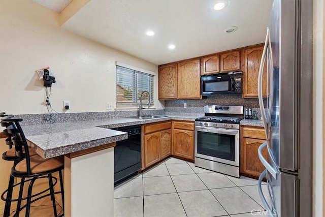 kitchen with sink, light tile patterned floors, a breakfast bar, black appliances, and decorative backsplash