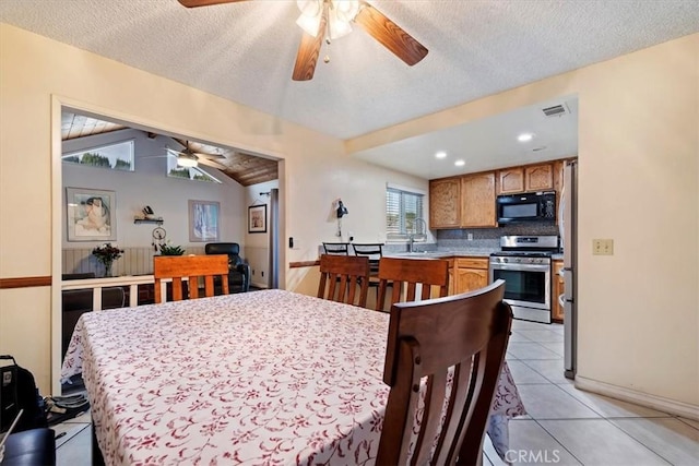 dining room featuring light tile patterned floors, a textured ceiling, vaulted ceiling, and ceiling fan