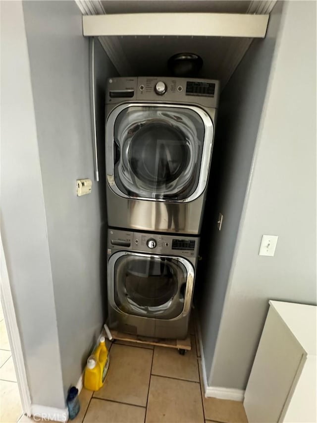 clothes washing area featuring stacked washer / dryer and light tile patterned flooring