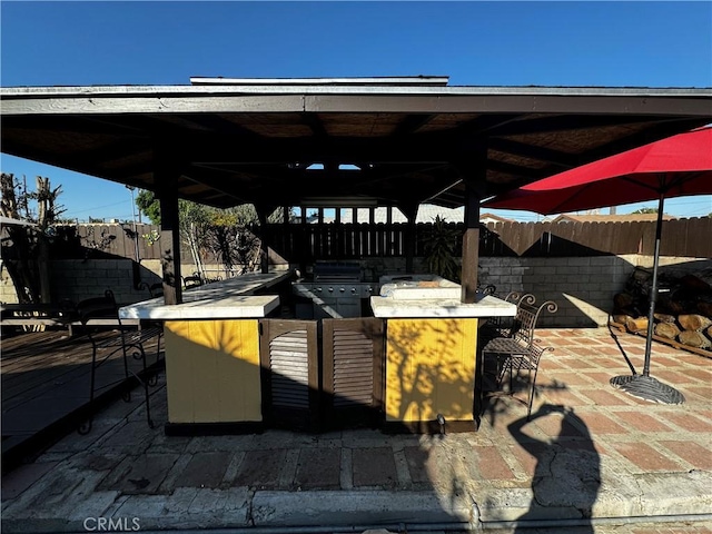 view of patio / terrace featuring exterior bar, an outdoor kitchen, and a grill