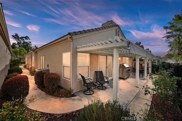 back house at dusk with a patio and a pergola