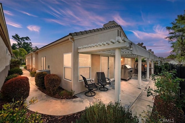 rear view of property featuring a patio area, a pergola, stucco siding, and a fenced backyard