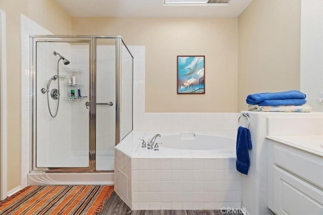 full bath featuring a stall shower, a garden tub, vanity, and wood finished floors