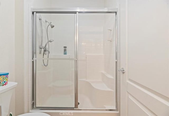 bathroom featuring toilet and a shower with door