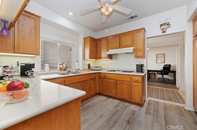 kitchen with visible vents, under cabinet range hood, light countertops, a sink, and white gas stovetop