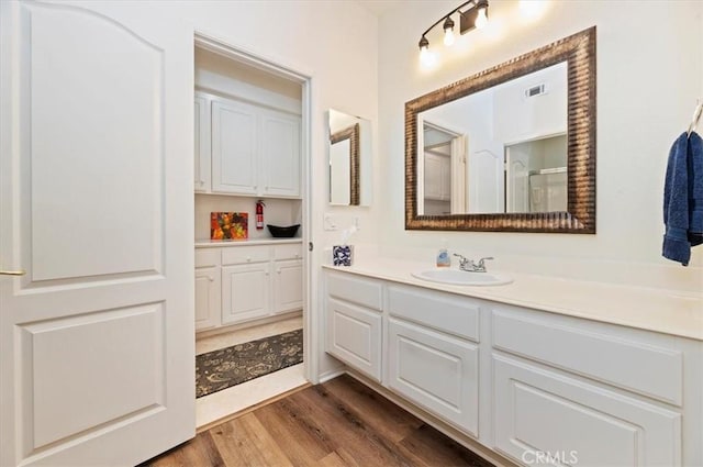 full bath with vanity, visible vents, and wood finished floors