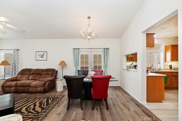 dining area with ceiling fan with notable chandelier and light hardwood / wood-style floors