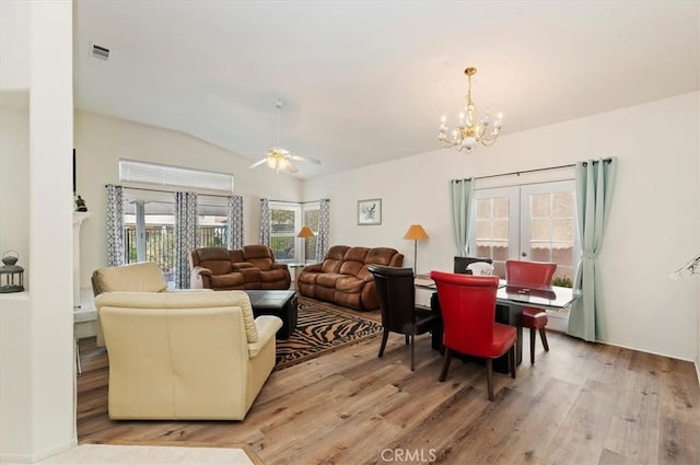 living area with lofted ceiling, visible vents, ceiling fan with notable chandelier, and wood finished floors