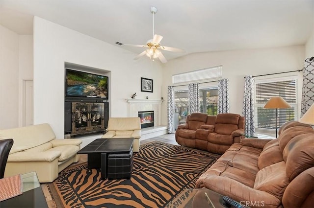 living room with a ceiling fan, visible vents, lofted ceiling, a high end fireplace, and wood finished floors