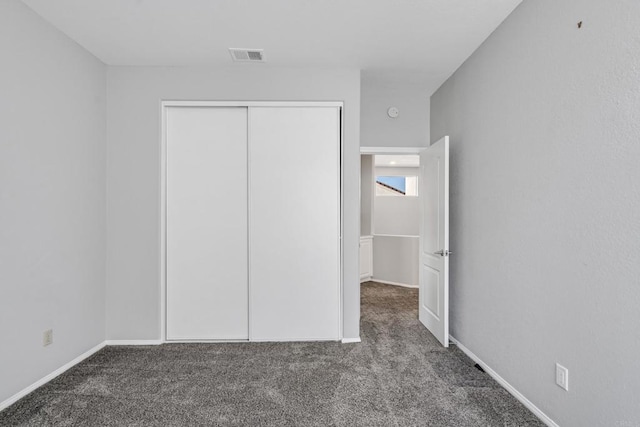 unfurnished bedroom featuring dark colored carpet and a closet