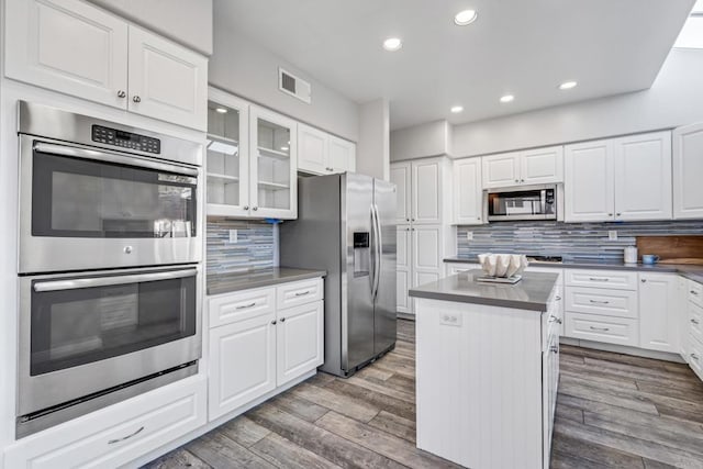 kitchen with a kitchen island, appliances with stainless steel finishes, backsplash, and white cabinetry