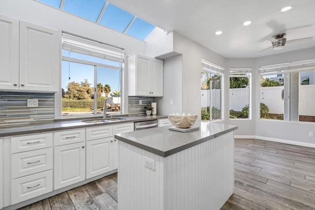 kitchen with stainless steel dishwasher, ceiling fan, tasteful backsplash, and white cabinetry