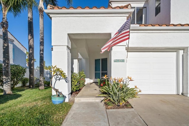 property entrance with a lawn and a garage