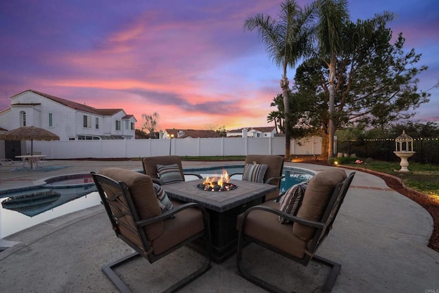 patio terrace at dusk featuring a fenced in pool and a fire pit