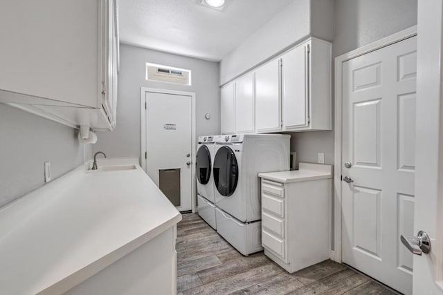 laundry room with cabinets, light hardwood / wood-style floors, washer and clothes dryer, and sink