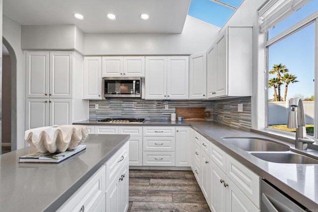 kitchen featuring tasteful backsplash, dark hardwood / wood-style flooring, white cabinetry, appliances with stainless steel finishes, and sink