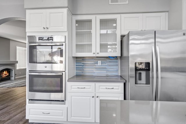 kitchen featuring appliances with stainless steel finishes, white cabinetry, dark hardwood / wood-style floors, and decorative backsplash