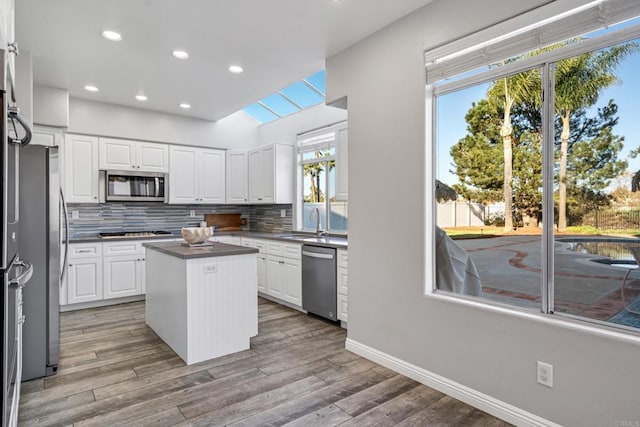 kitchen featuring white cabinets, stainless steel appliances, a center island, and decorative backsplash