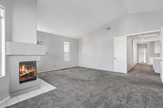 unfurnished living room featuring vaulted ceiling, a multi sided fireplace, and light carpet