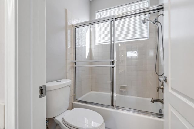 bathroom with toilet and combined bath / shower with glass door