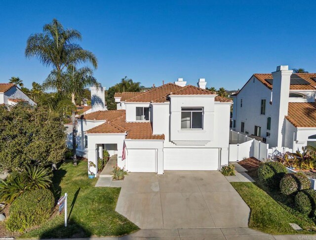 mediterranean / spanish house featuring a garage, concrete driveway, a tiled roof, fence, and stucco siding