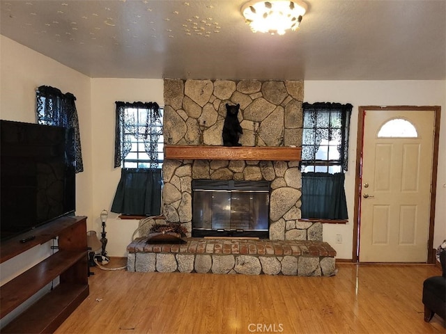 unfurnished living room featuring wood-type flooring and a stone fireplace