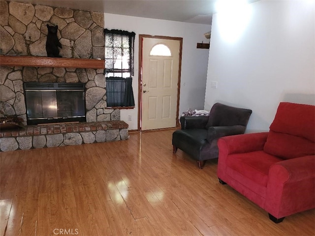 living room with a stone fireplace and light wood-type flooring