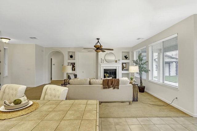 living room featuring ceiling fan, light colored carpet, and built in features