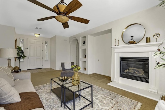 living room with ceiling fan, built in features, and light carpet