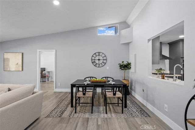 dining space with vaulted ceiling and light wood-type flooring