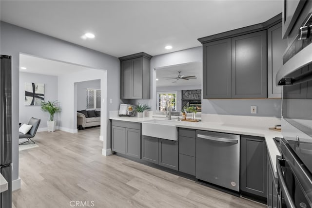 kitchen with gray cabinetry, sink, stainless steel appliances, and light wood-type flooring