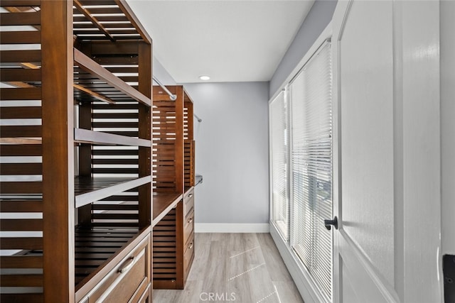 walk in closet with light hardwood / wood-style floors