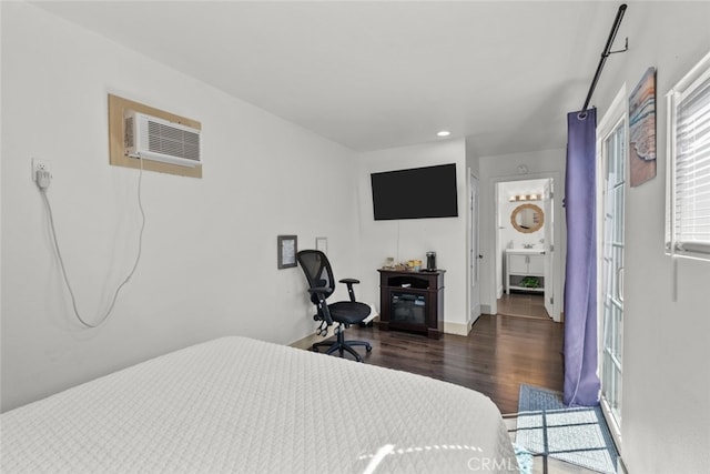 bedroom with a wall mounted air conditioner, dark hardwood / wood-style flooring, and connected bathroom