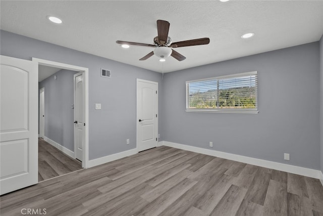 unfurnished bedroom featuring ceiling fan, light hardwood / wood-style flooring, and a textured ceiling