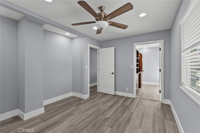 unfurnished bedroom with a spacious closet, light hardwood / wood-style flooring, and ceiling fan