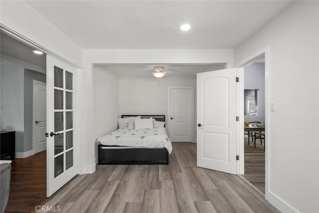 bedroom featuring french doors, a textured ceiling, and light wood-type flooring