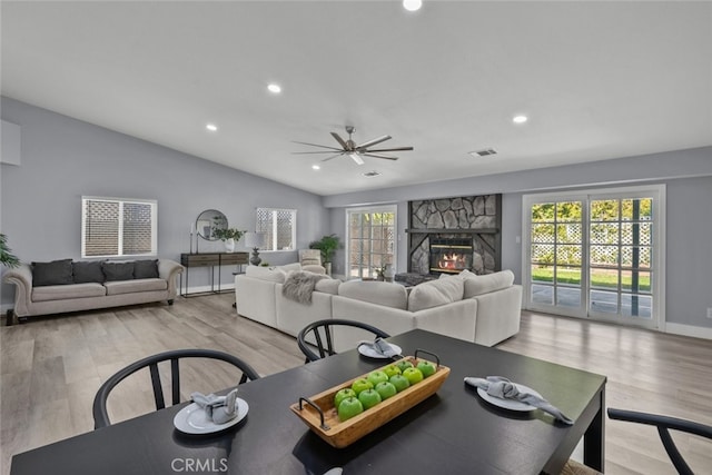 living room featuring ceiling fan, lofted ceiling, a fireplace, and light hardwood / wood-style floors