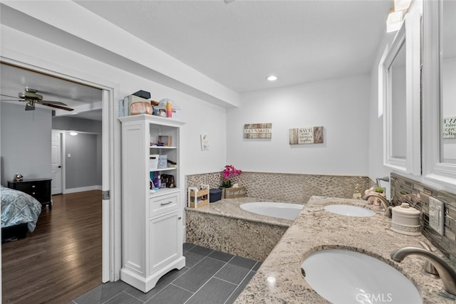 bathroom featuring vanity, wood-type flooring, a relaxing tiled tub, and ceiling fan