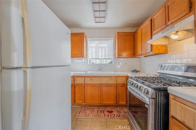 kitchen featuring tile counters, white fridge, sink, light tile patterned flooring, and gas range