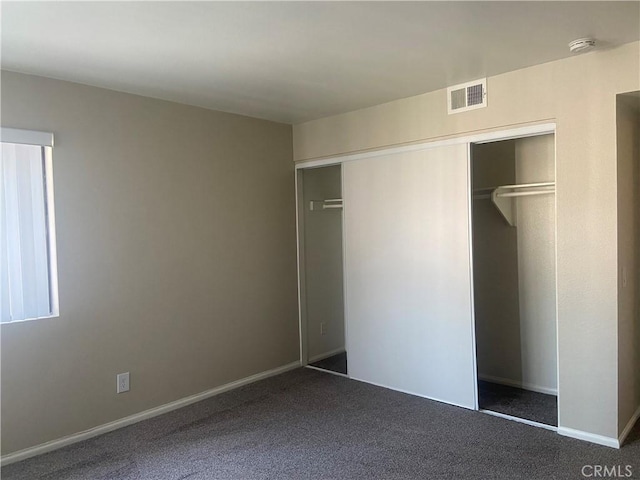 unfurnished bedroom featuring a closet and dark colored carpet