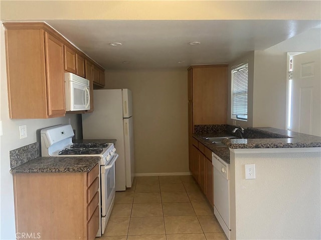 kitchen featuring dark stone countertops, kitchen peninsula, sink, white appliances, and light tile patterned floors