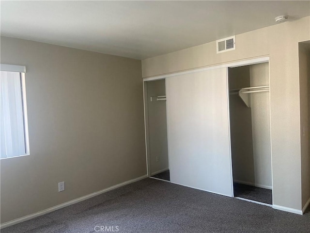 unfurnished bedroom featuring a closet and dark colored carpet