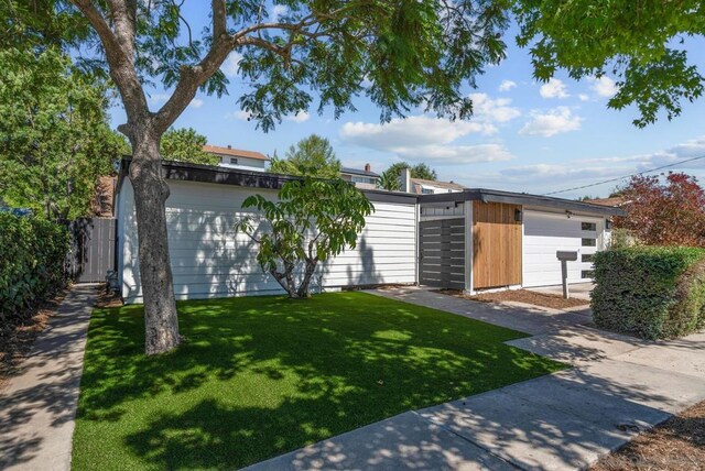 view of front facade featuring a garage, a front yard, and an outdoor structure